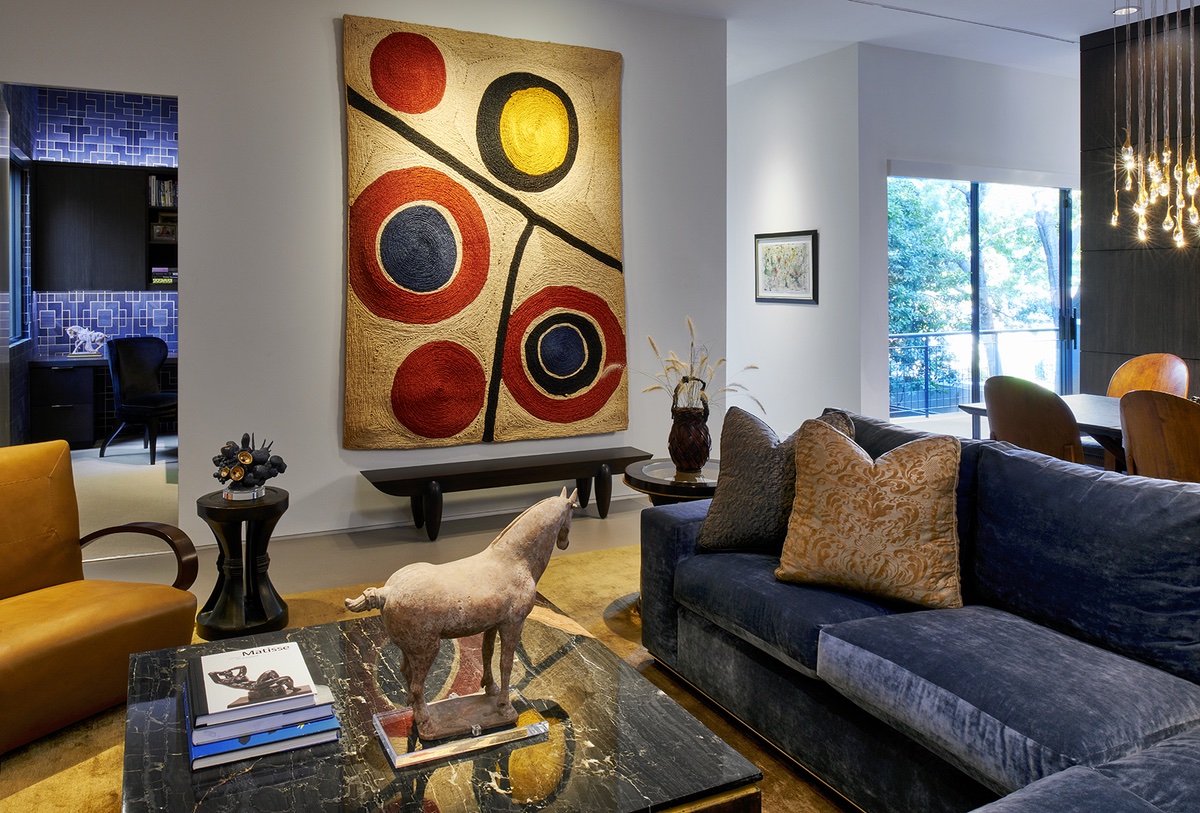 Living room area with blue sofas and large woven run art piece hanging like a painting on the wall