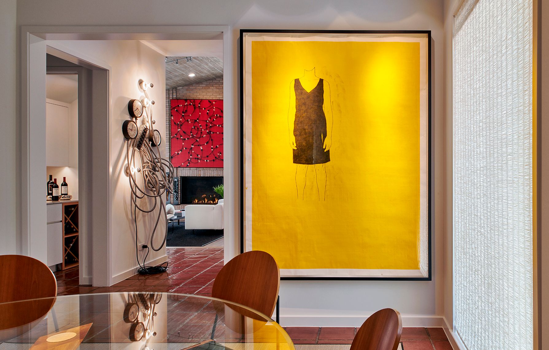 dining area with round glass table and large yellow painting on wall nearby