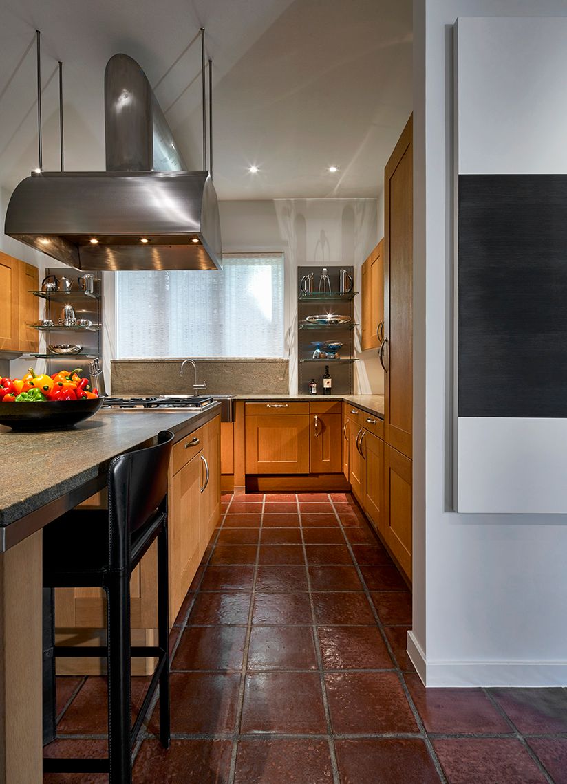 view of dark tiled kitchen with stainless over range hood